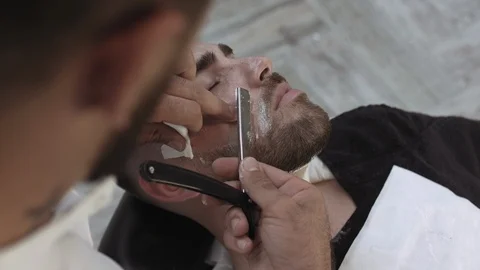 Close up top view of a professional young male hairdresser shaving beard Stock Footage 112341654