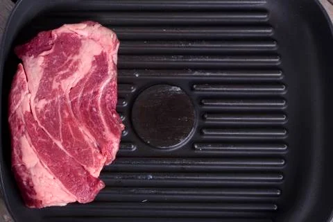 Close-up top view of raw beef steak on grill pan. Copy space. Receipt concept Stock Photos