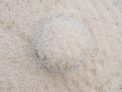 Close up top view rice in a white bowl and scattered near on wooden table wit Stock Photos