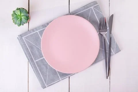 Close-up top view of serving empty pink plate, knife and fork on linen napkin Stock Photos