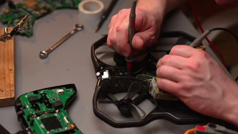 Close-up top view of technician hands testing circuits of disassembled fpv drone Stock Footage 302565326