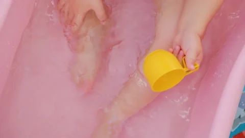 Close up top view unrecognizable feet and hands of a baby in a bath, plays with Stock Footage 208434060