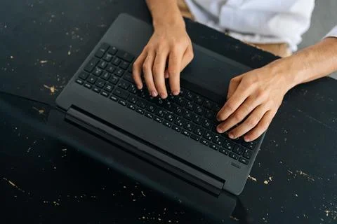 Close-up top view of unrecognizable young man typing texting on modern laptop Stock Photos