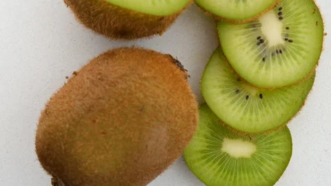 Close-up top view of whole and sliced kiwi rotating clockwise Stock Footage 272253003