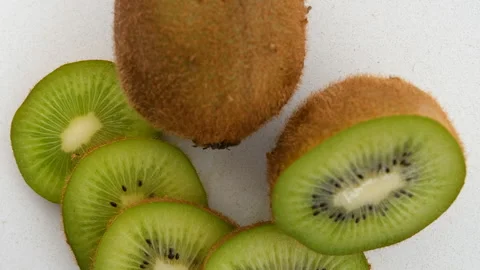 Close-up top view of whole and sliced kiwi rotating counterclockwise Stock Footage 272253138