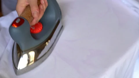 Close-up top view of woman's hand holding electric device and ironing clothes Stock Footage 121383443
