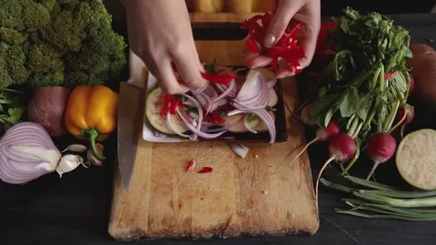 Close up of a top view of a woman's hands placing chunks of red pepper on a s Stock Footage 145242221