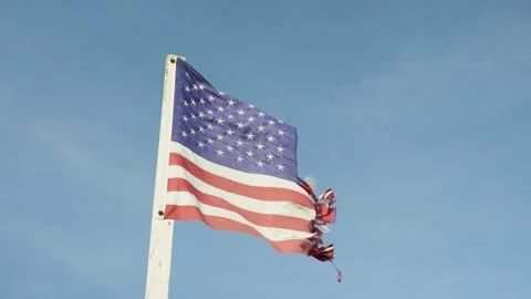 Close-up of a torn American flag fluttering in the wind against blue sky. Stock-Footage 321344244