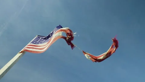 Close-up of a torn American flag fluttering in the wind against blue sky. Stock Footage 321344491
