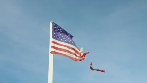 Close-up of a torn American flag fluttering in the wind against blue sky. Stock Footage 321344920