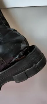 Close up of a torn black leather boot with a broken sole. Foto stock