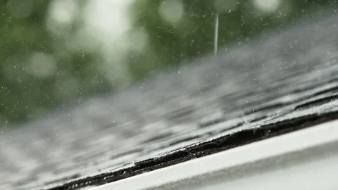 Close-up of a torrential rain falling on a shingled roof of a residential home Stock Footage 112613363