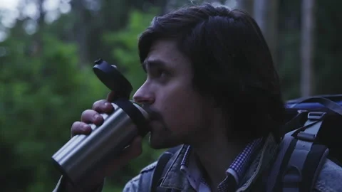 Close-up: A tourist with a backpack drinks from a thermos. Profile, night forest Stock-Footage 201129642
