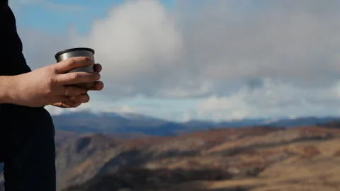 Close-up of a tourist's hands with a cup of coffee in the mountains. Stock Footage 288280247