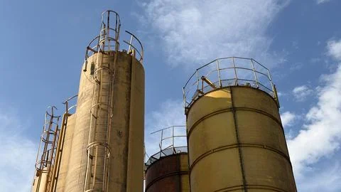Close-up of towering yellow and rusty industrial silos featuring weathered Stock Photos