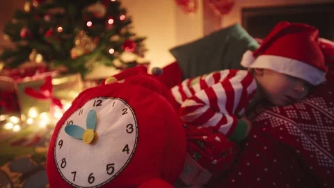Close up of toy clock and sleeping little boy dreaming about Santa. Christmas Stock Footage 73028278
