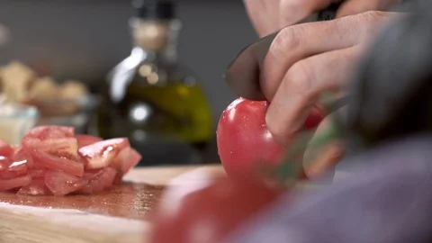 Close-up tracking shot of chef slicing ripe tomato on cutting board Stockbeeldmateriaal 92211006