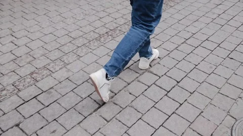 Close-up tracking shot of the legs of a man in white sneakers and a jeans Stock Footage 170611852
