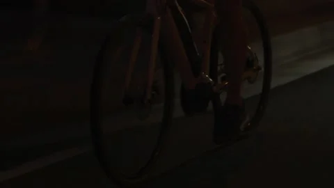 Close up tracking shot of man riding road bike at night on street Stock Footage 227450554