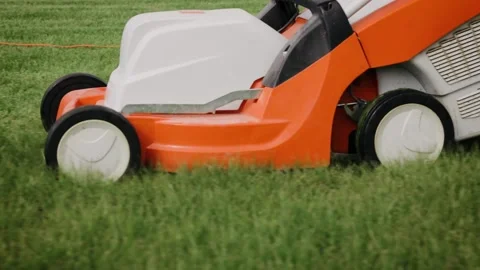 Close up tracking shot of a mowing the grass in the backyard with an electric Stock Footage 163033432