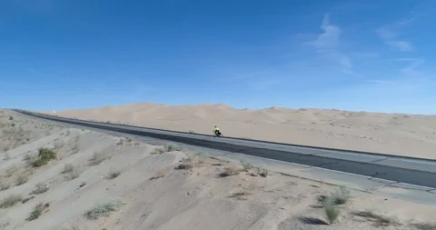 Close tracking shot shows cyclist with sand dunes drone aerial 4K Stock Footage 111309346