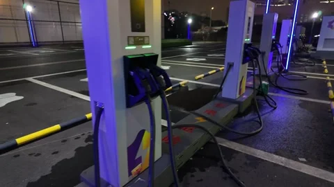 A close-up tracking shot of smart EV charging piles at night. Video stock 330883945
