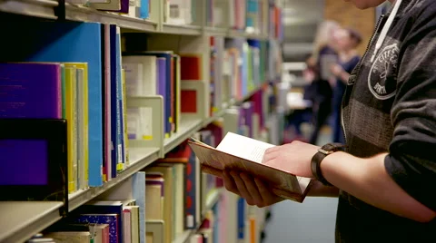 Close Tracking Student as he Chooses a Library Book Stock Footage 61639464