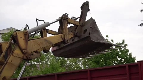 Close-up of a tractor bucket loads garbage into a trailer Stock Footage 154555171