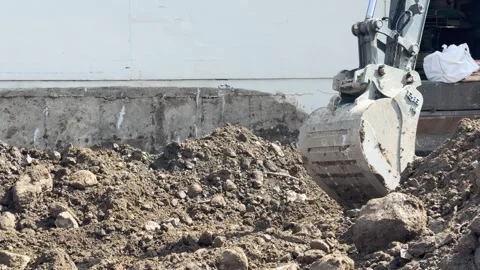 Close-up of a tractor front loader dragging its scoop along the ground, pulling Stock Footage 309000542
