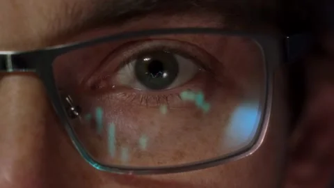 Close-up of a trader eye with financial graphs reflecting in his eyeglasses Stock Footage 313057035