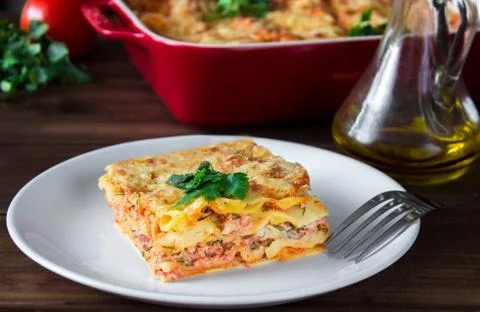 Close-up of a traditional lasagna topped with parskey leafs served on a white Stock Photos