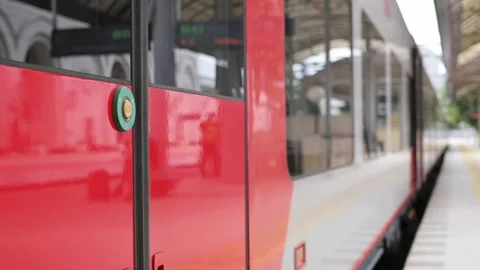 A close-up of a train car door with an open button at the station and guy Stockbeeldmateriaal 212075802