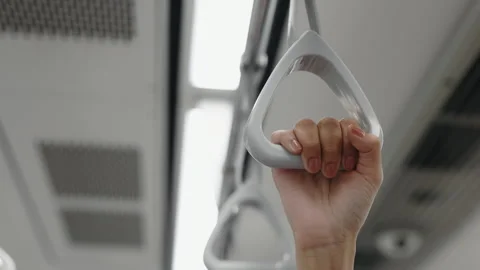 Close-up of a train passenger's hands, firmly gripping a gray handle with Vidéo 262393374