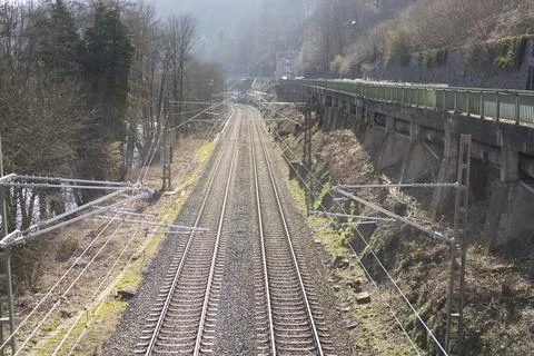 A close-up train tracks with power lines next to a stone wall. Railway transp Foto stock