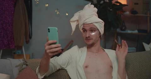 Close up of transgender sitting on couch while having video chat on smartphone Stock Photos