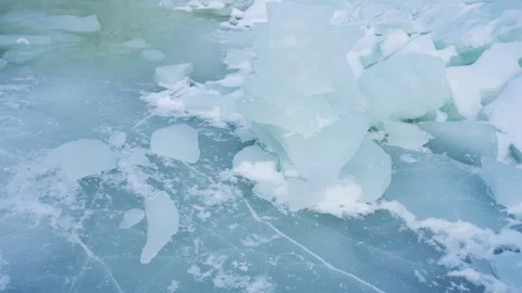 Close-up of translucent blue ice slabs and broken floes beside a pale meltwater Video stock 332045902