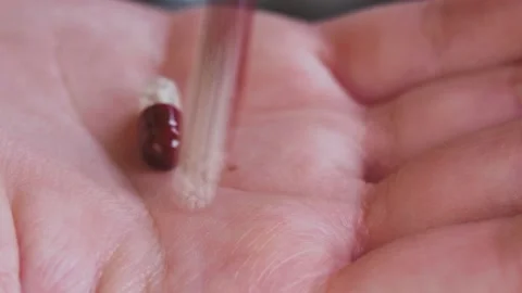 Close-up of translucent capsules with medicine fall into the hand Stock Footage 201445030