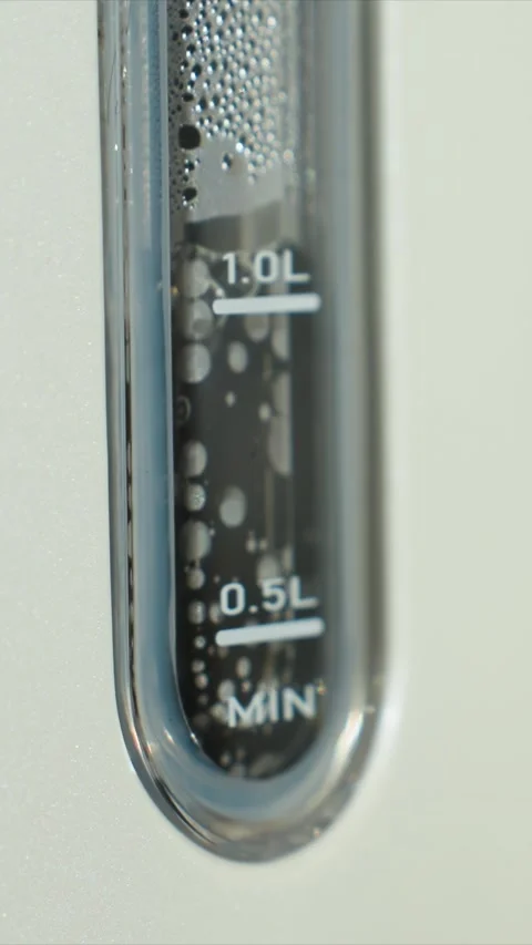 Close up of transparent cylindrical container showing dark liquid and rising Stock-Footage 345670660