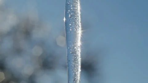 Close-up of a transparent icicle with trapped air bubbles and sunlight Stock Footage 303666038