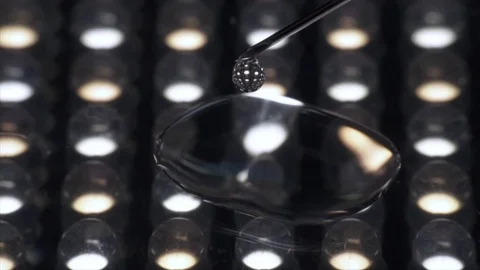 Close-up transparent liquid dripping from syringe needle isolated at lights 動画素材 103545821