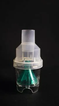 A close-up of a transparent plastic nebulizer cup with a green internal com.. Foto stock