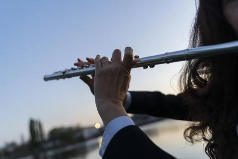 Close-up of a transverse flute in the hands of a middle-aged musician at su.. Stock Photos