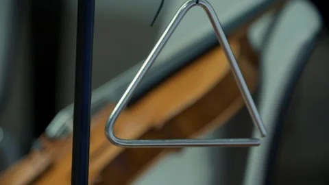 Close up of triangle musical instrument hanging with a violin in the background Stock Footage 342938492