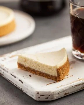 Close-up of a triangular slice of cheesecake cake on a white wooden tray. Foto stock
