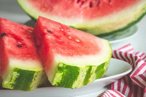 Close up of triangular slices of ripe watermelon with red flesh served on whi Stock Photos