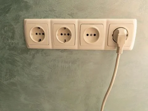 Close-up of a triple wall power socket, with one outlet in use and a white .. Фото