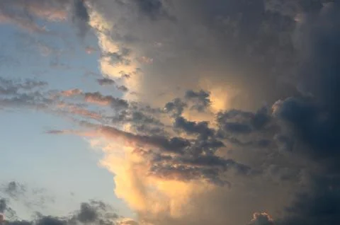 Close-up of turbulent cloud formations and amber sunbeams at twilight 스톡 사진