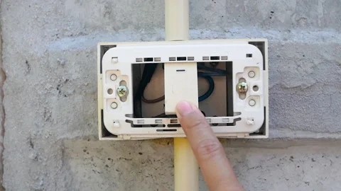 Close-up of turning on and turning off worn-out wall switch light on cement wall 스톡 동영상 136494482