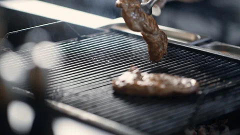 Close up turning meat steak on grill surrounded by steam. Shot on RED Raven 4k Stock Footage 124866027