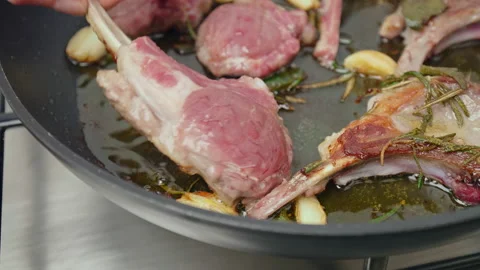 Close-up turning on the other side lamb ribs cutlets in a frying pan with greens Stock Footage 145999269